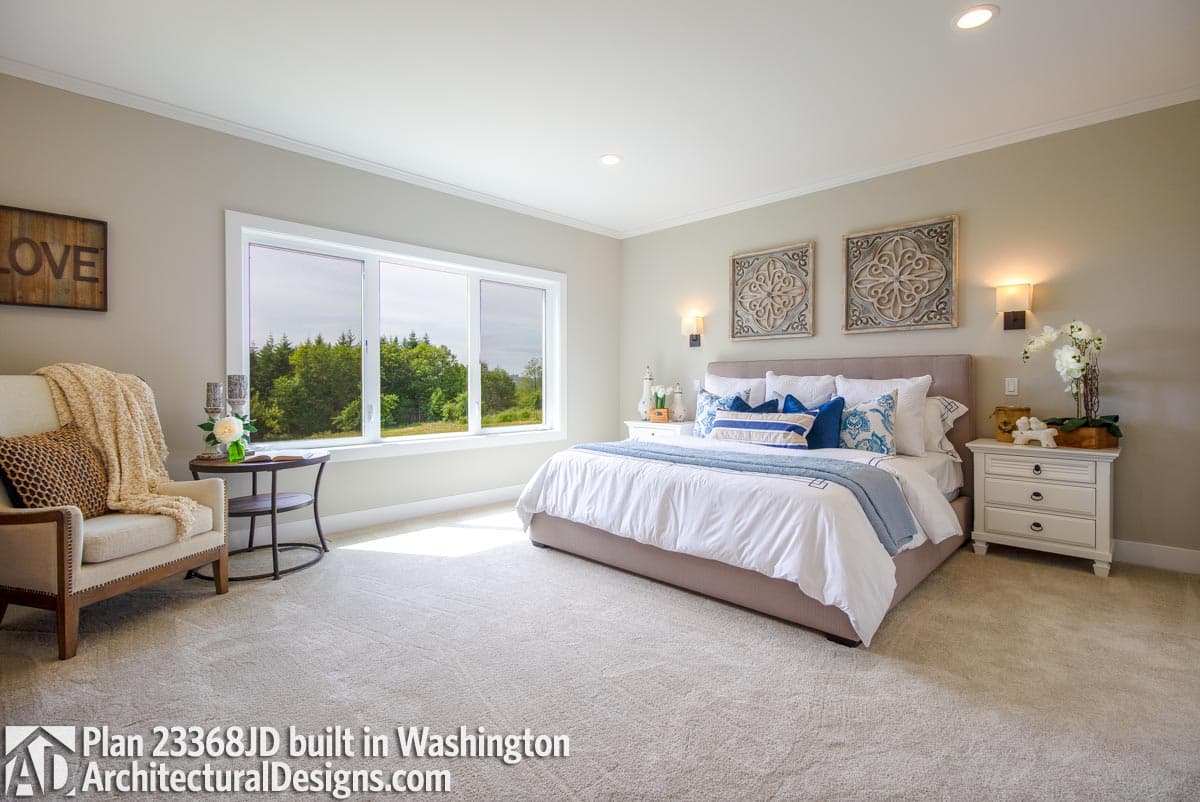Primary bedroom with king bed, wide horizontal windows overlooking trees, and accent wall art.