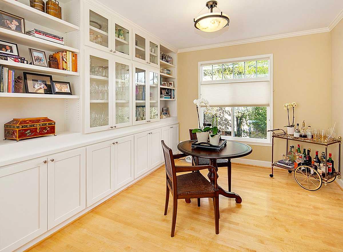 Interior view of dining area with built-in shelving, a round table with two chairs, and a bar cart.