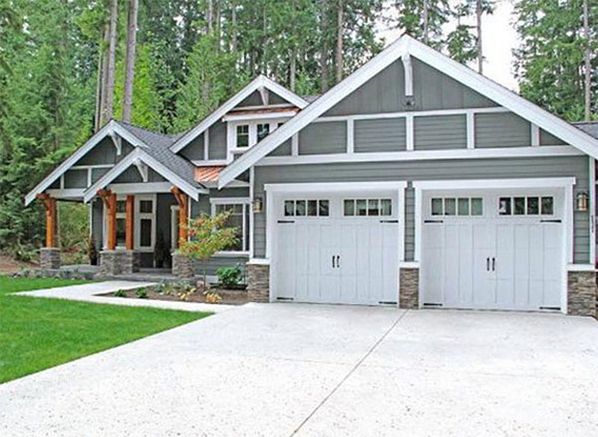 House plan exterior featuring a covered porch with timber posts, dual garage doors, gabled rooflines, and stone accents.