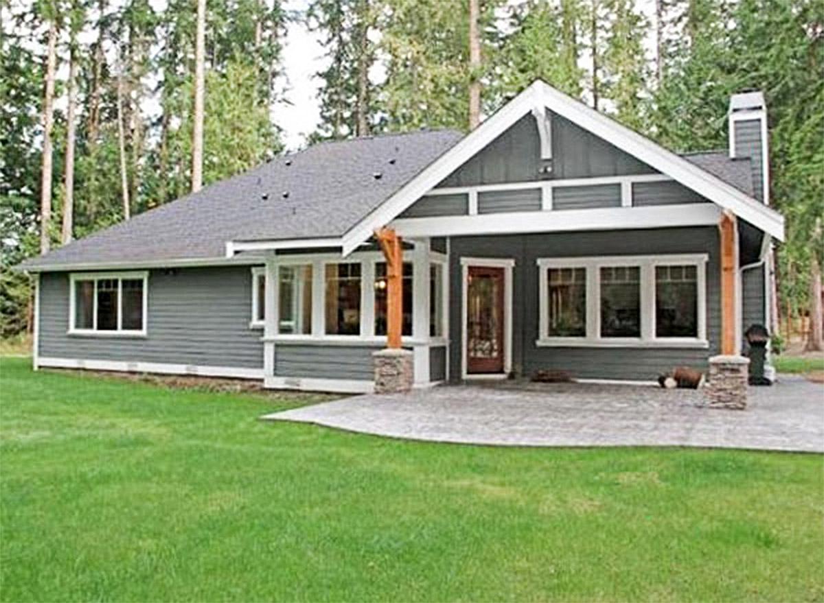 Craftsman style house plan exterior. Single story with covered entry, stone columns, wide eaves, and lap siding.