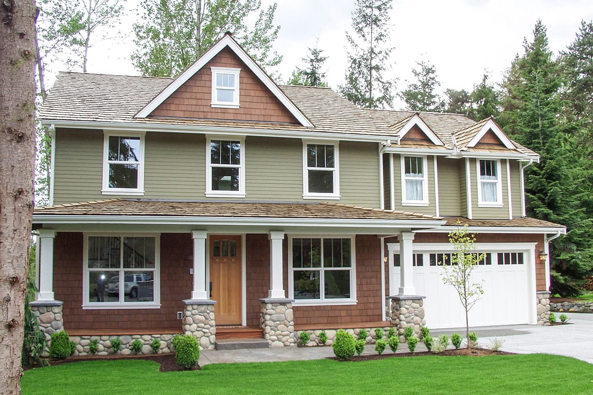 Two-story house plan exterior with covered porch supported by stone-clad columns, multiple gables, and a two-car garage.