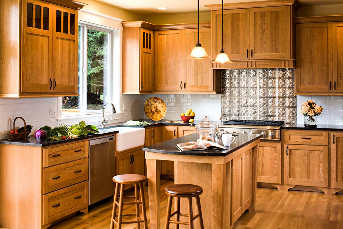 Kitchen with natural wood cabinets, granite countertops, a farmhouse sink, and a central island with bar stools.