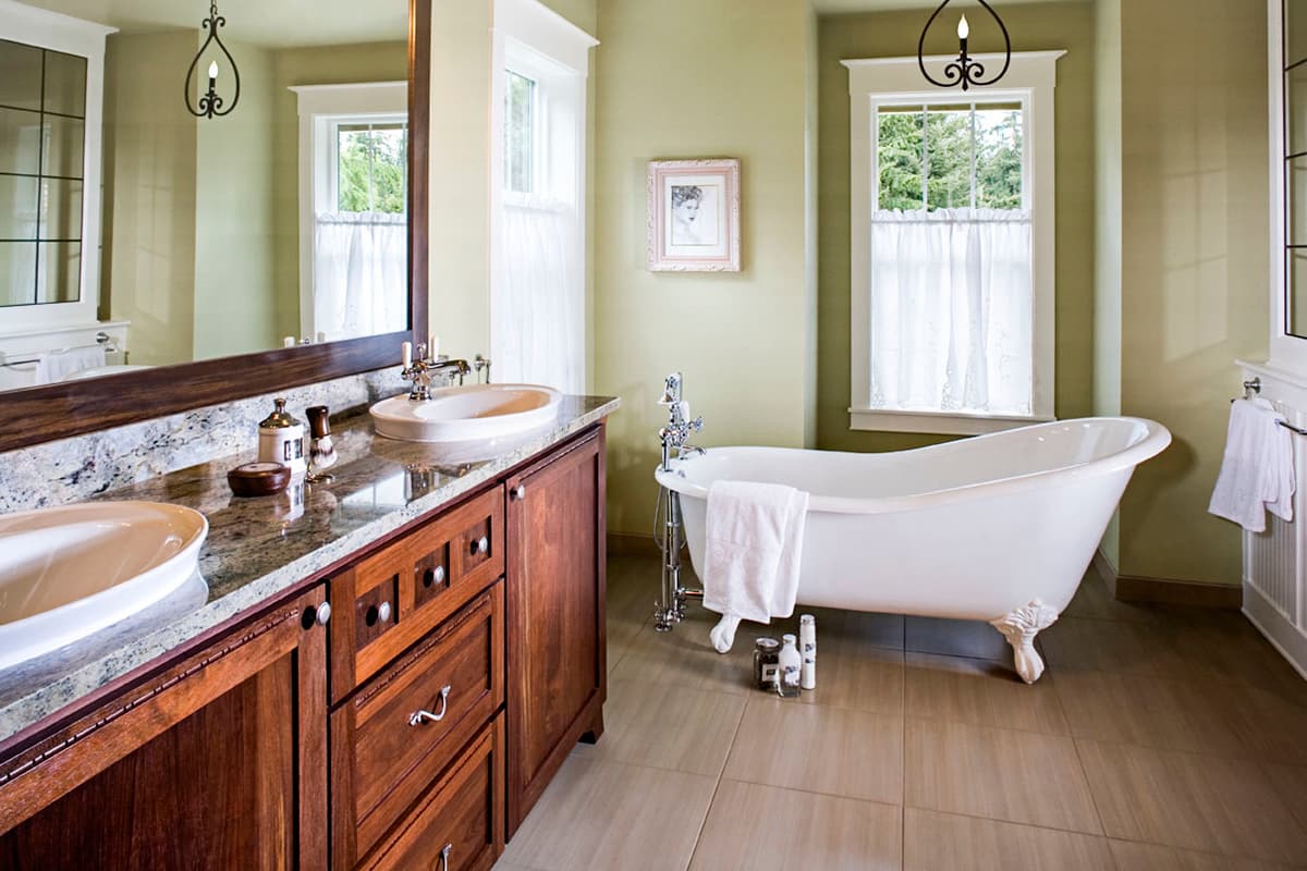 Bathroom with dual sinks, granite countertop, wood vanity, and freestanding clawfoot tub.