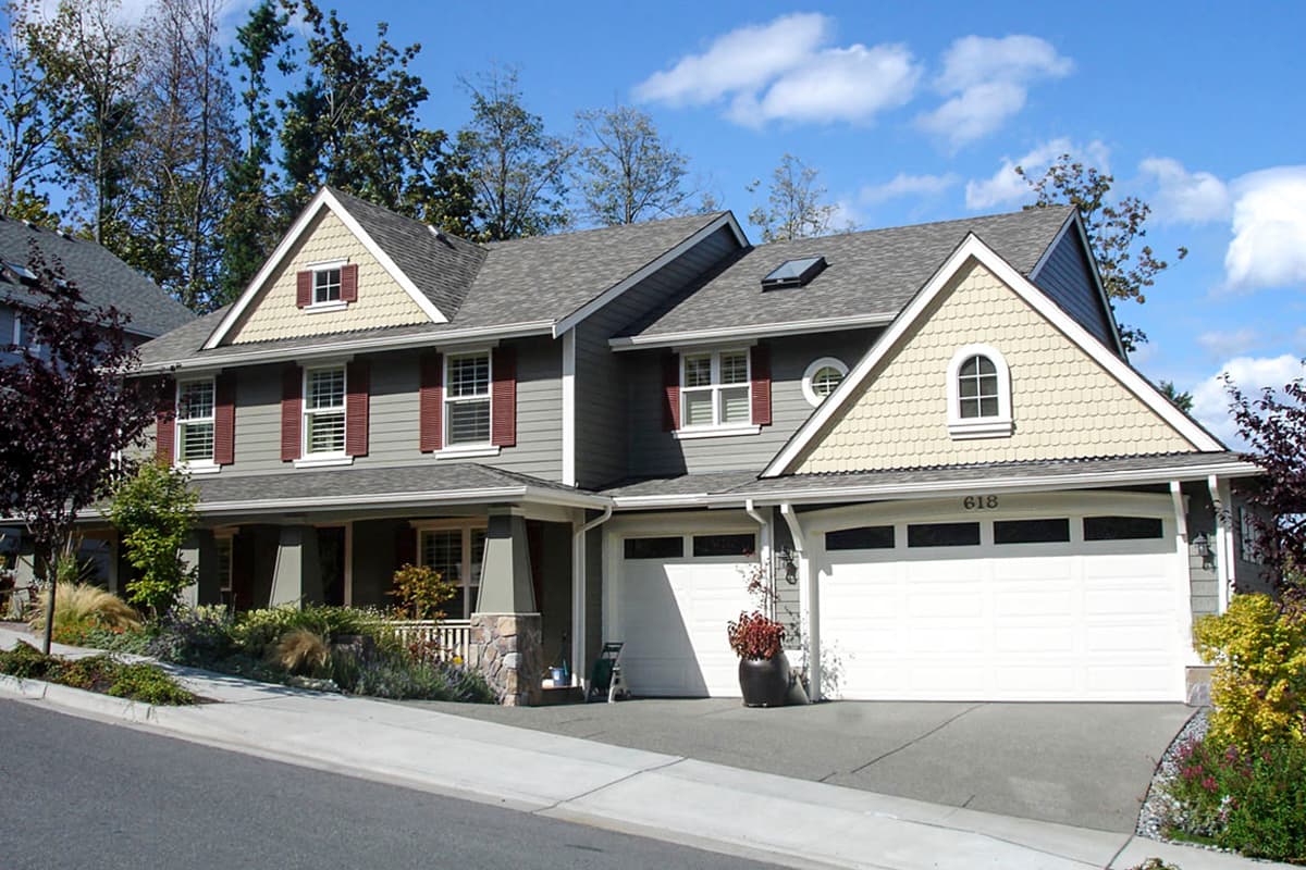 House plan exterior of two-story home with covered front porch, dormers, and attached two-car garage.