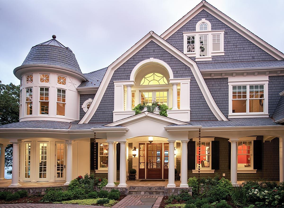 House plan exterior: Two-story home with shingled gables, turret, arched dormer, and covered porch with columns.