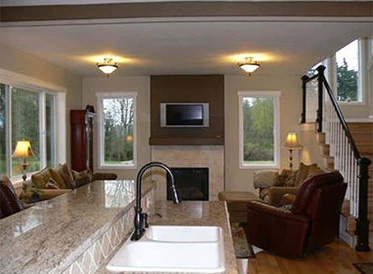 Interior view of open-concept living space with kitchen island, fireplace, and stairs.