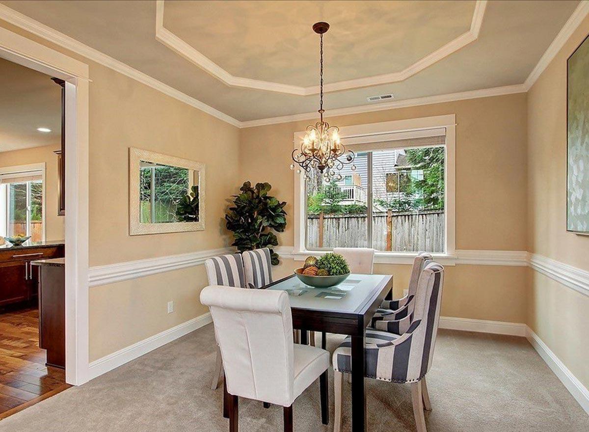 Dining room with octagonal coffered ceiling, glass-top table, upholstered chairs, and a large window overlooking the backyard.