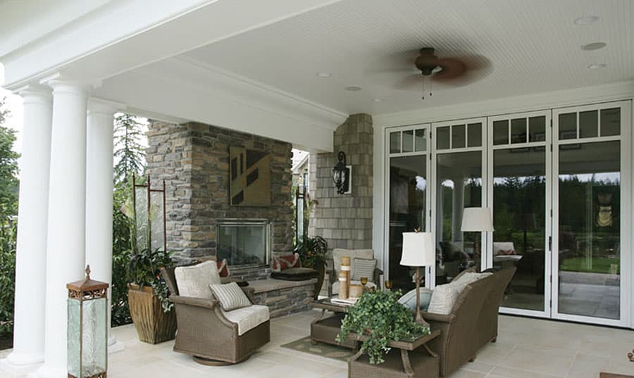 Covered patio with stone fireplace, seating, and folding glass doors.