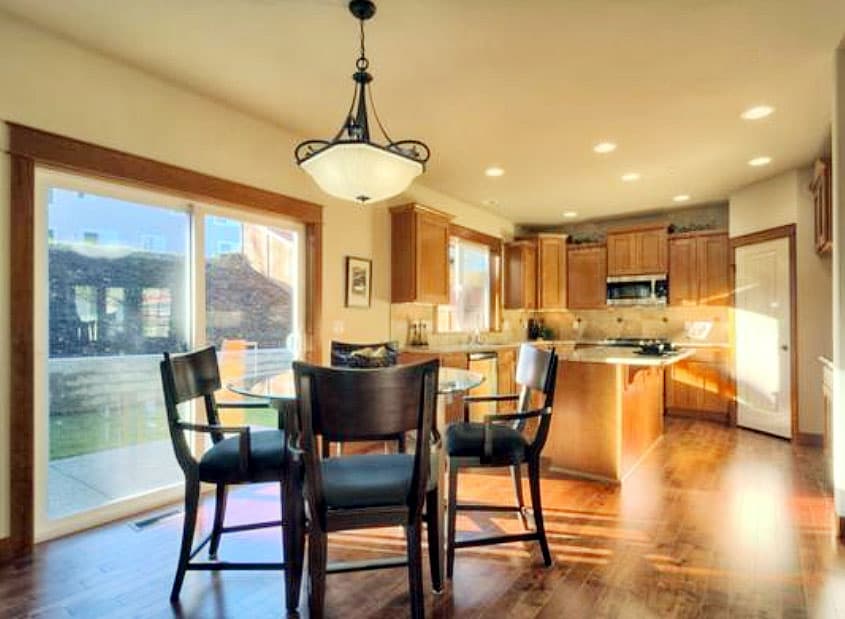 Interior view of kitchen and dining area. Features include wood cabinetry, island with countertop, and sliding glass door.