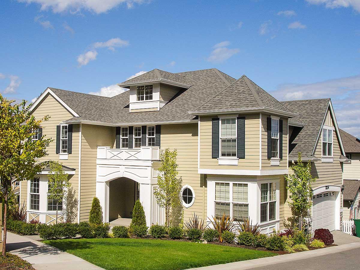House plan exterior: two-story home with a prominent arched entryway, multi-level gables, dormer, and bay window.