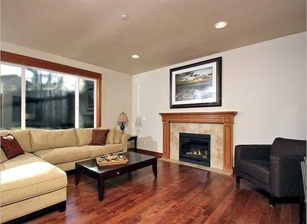 Living room with sectional sofa, dark wood coffee table, fireplace, and large window.