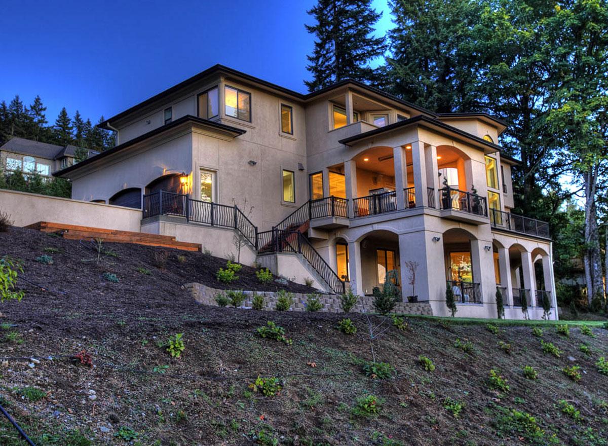House plan exterior: Three-story stucco home with covered balconies, arched openings on the lower level, and a multi-level roofline.