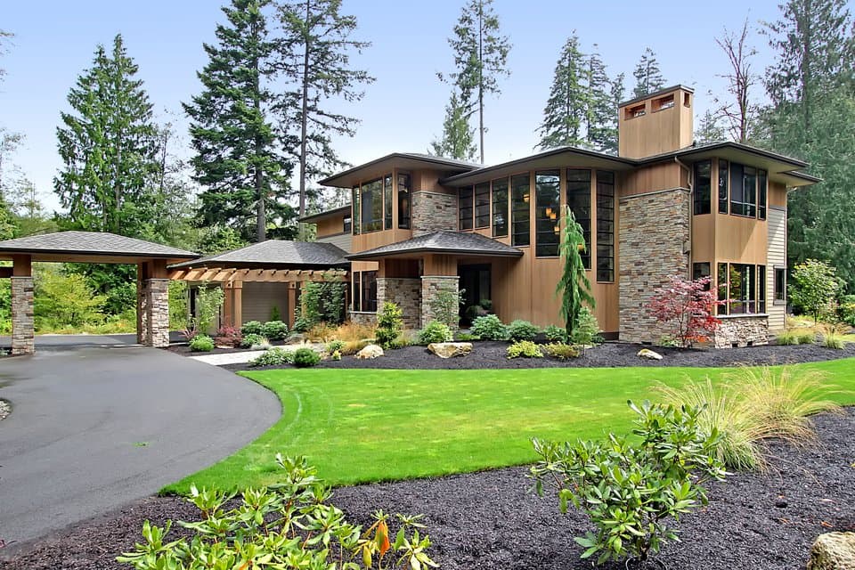 Modern house plan exterior with wood siding, stone accents, multi-level rooflines, and carport.