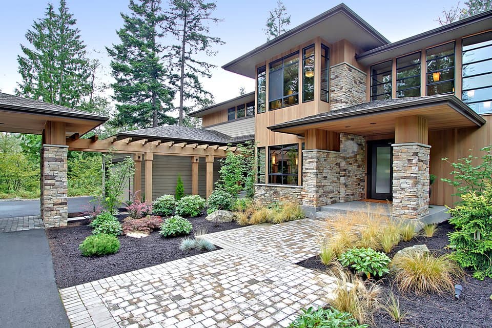 Modern house plan exterior with wood siding, stone accents, large windows, covered entryway, and pergola connecting to garage.