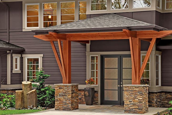 House plan exterior with stone-clad columns supporting a wood pergola over a double-door entry.