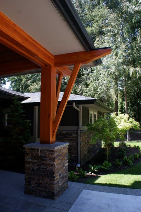 House plan exterior featuring a stone-clad pillar supporting a wooden beam and overhang with exposed rafters.