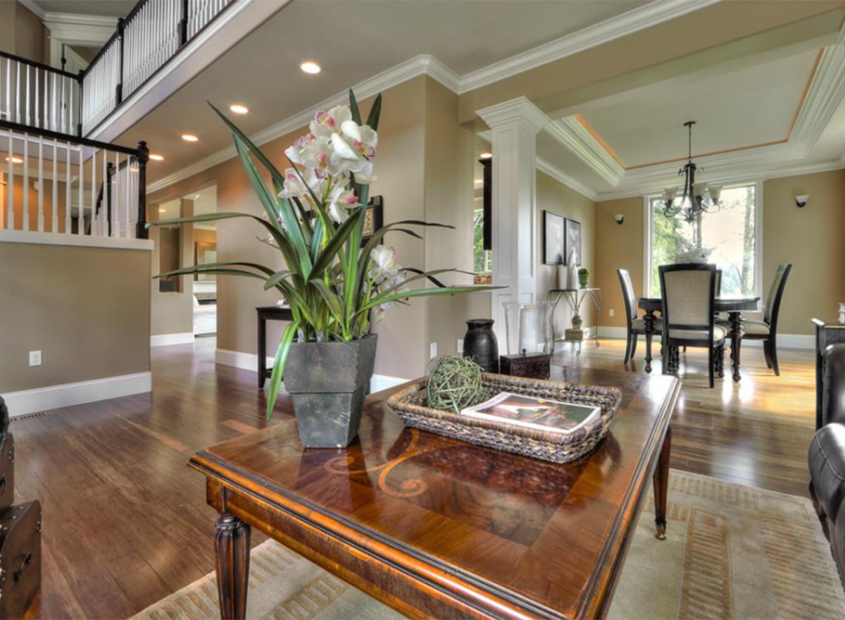 Interior view of open-concept living space with tray ceiling, dining area, and staircase with white spindles.