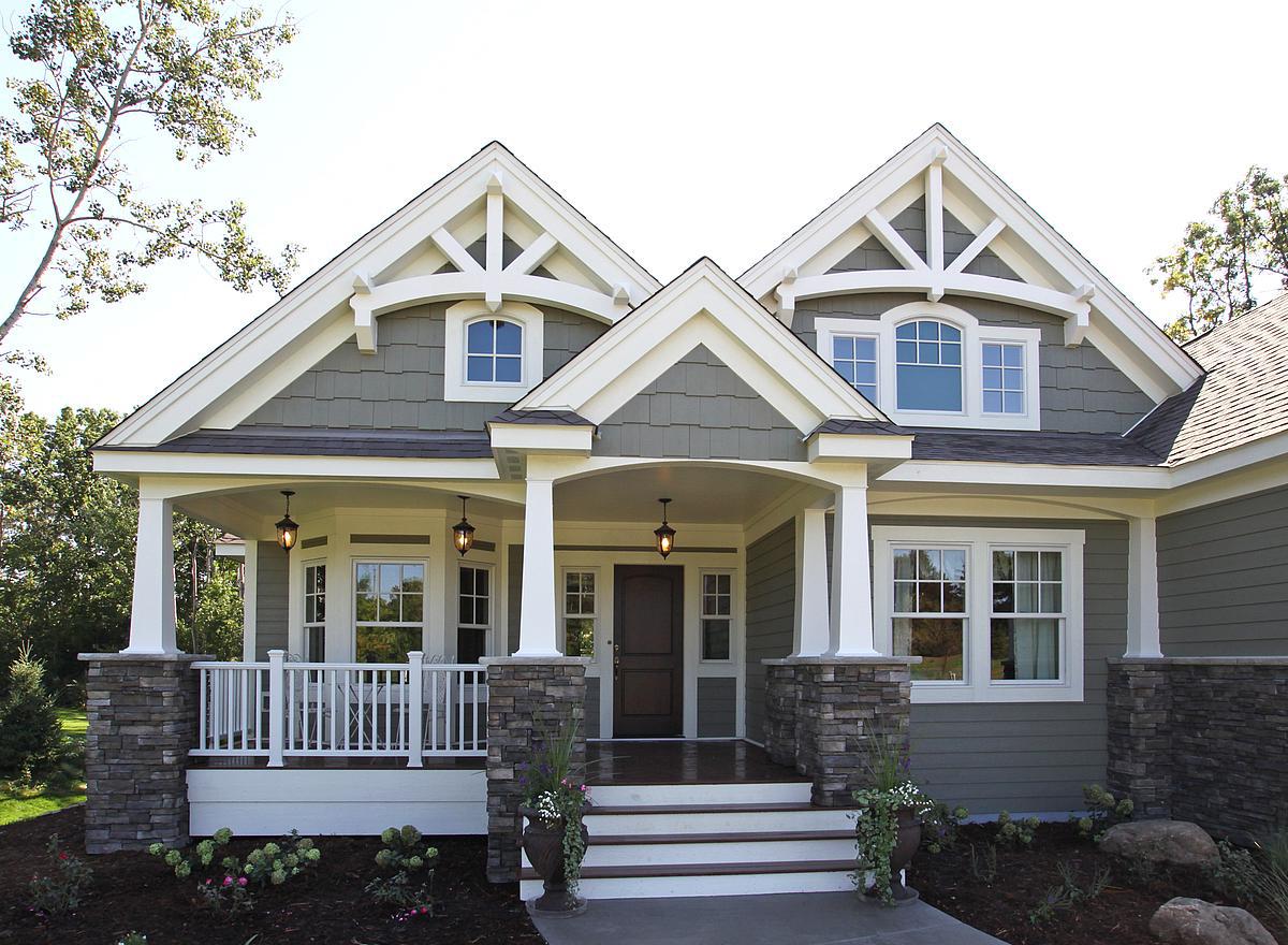 Craftsman-style house plan exterior with a covered porch, stone pillars, multiple gables, and decorative roof trusses.