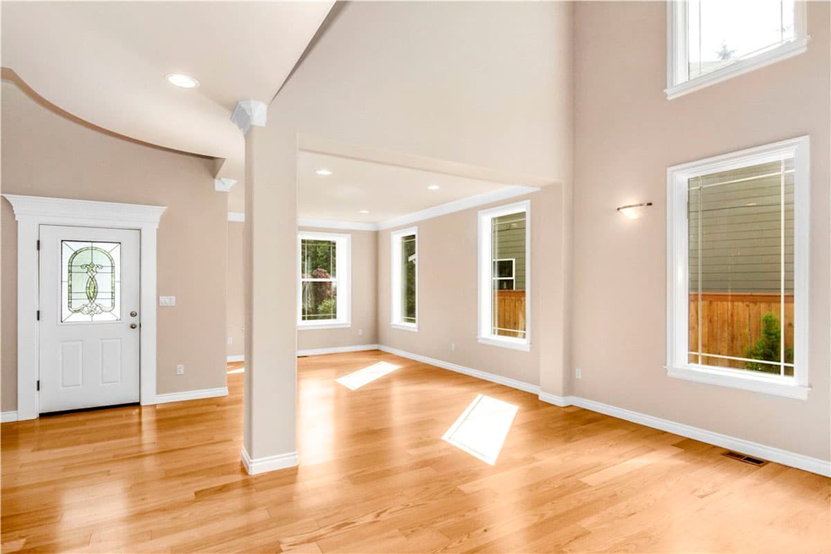 Interior view showing a grand entrance with decorative glass door, open layout, large windows, and vaulted ceiling.