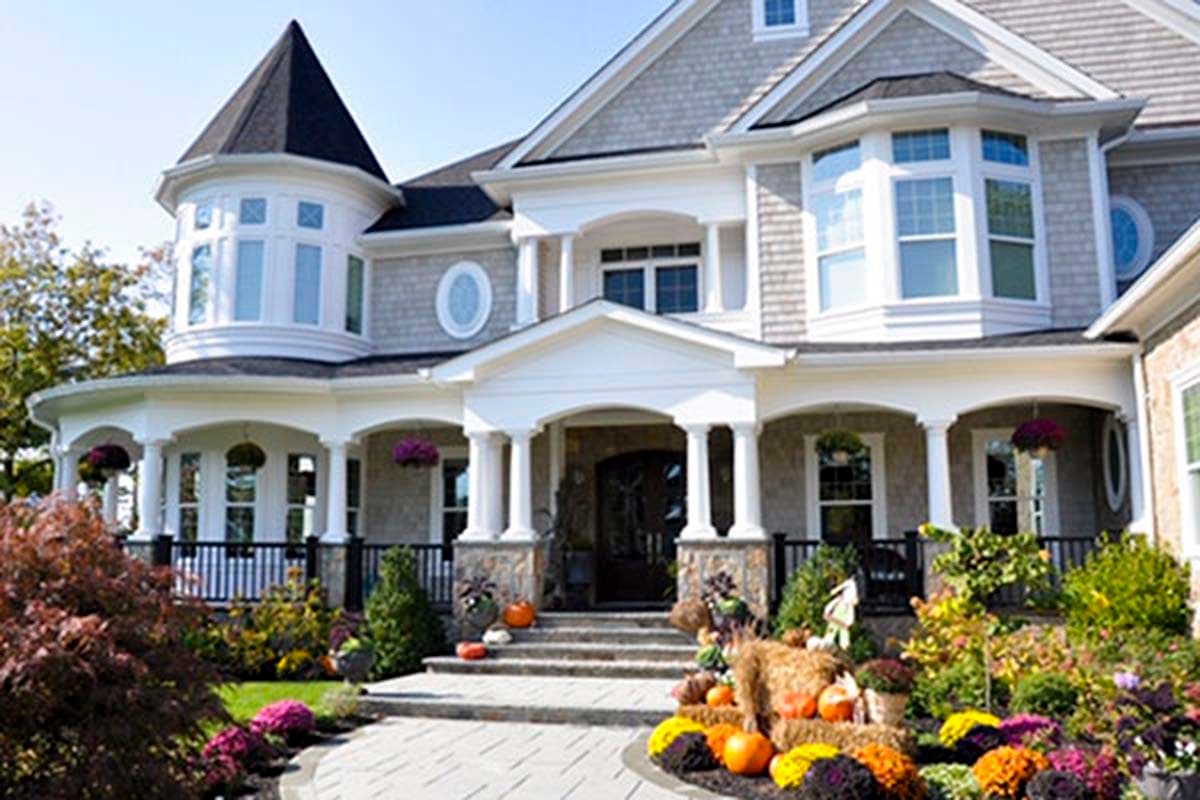 House plan exterior: two-story home with turrets, bay windows, covered porch with columns, and prominent gables.