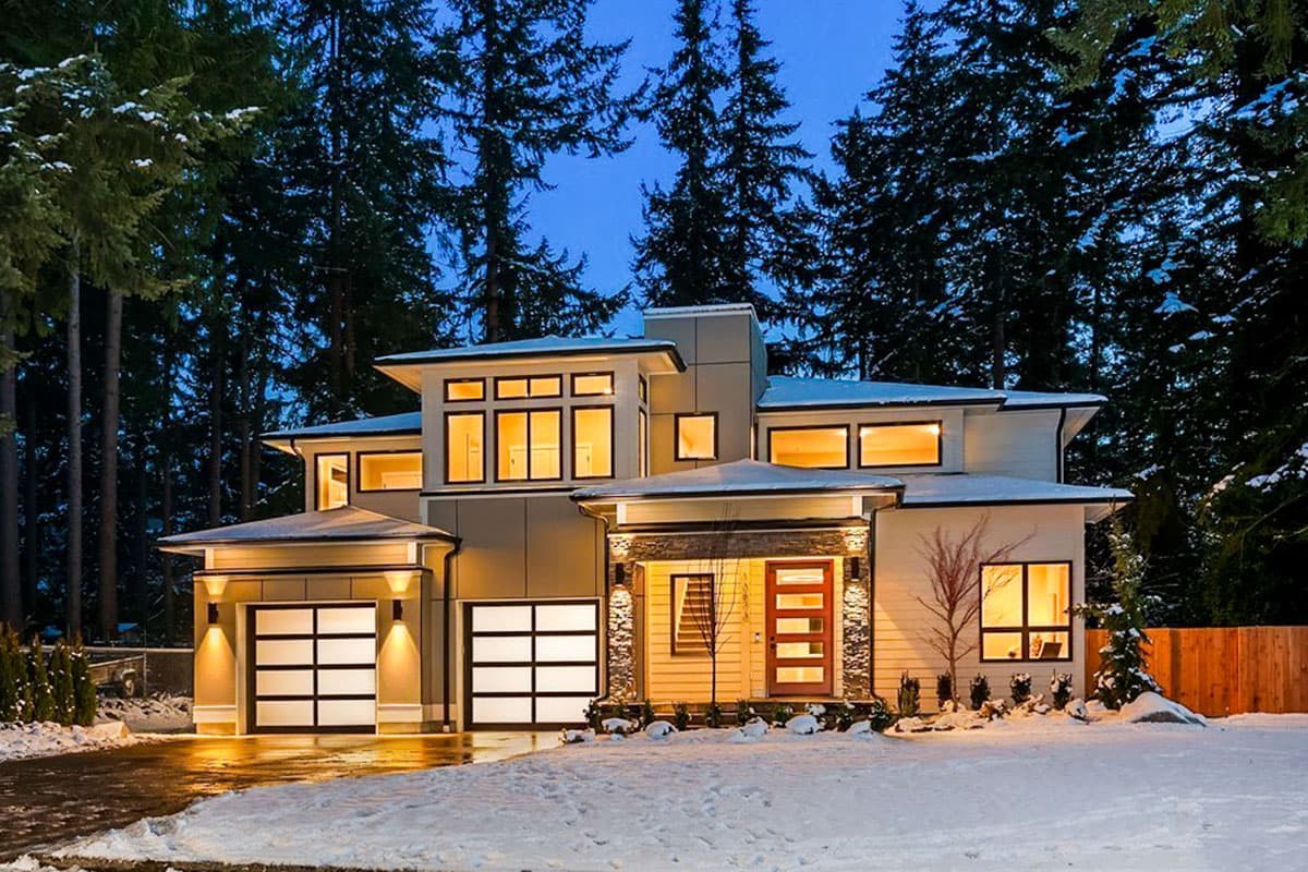 Modern house plan exterior with dual garage doors, covered entryway with stone accents, and multiple large windows.