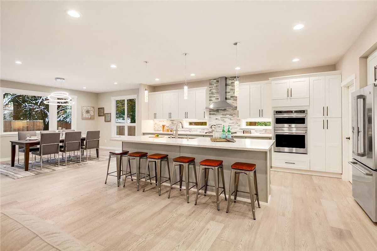 Modern kitchen and dining area with large island, stainless steel appliances, and view of outdoor winter scenery.