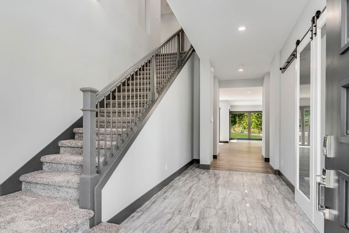 Interior view of entryway with carpeted staircase, marble tile floor, and sliding barn door.