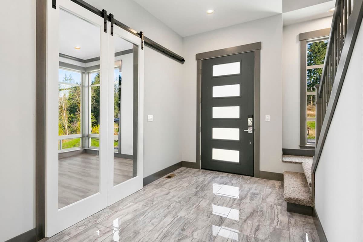 Interior view of entry with modern door, sliding mirror doors, and staircase to upper level.