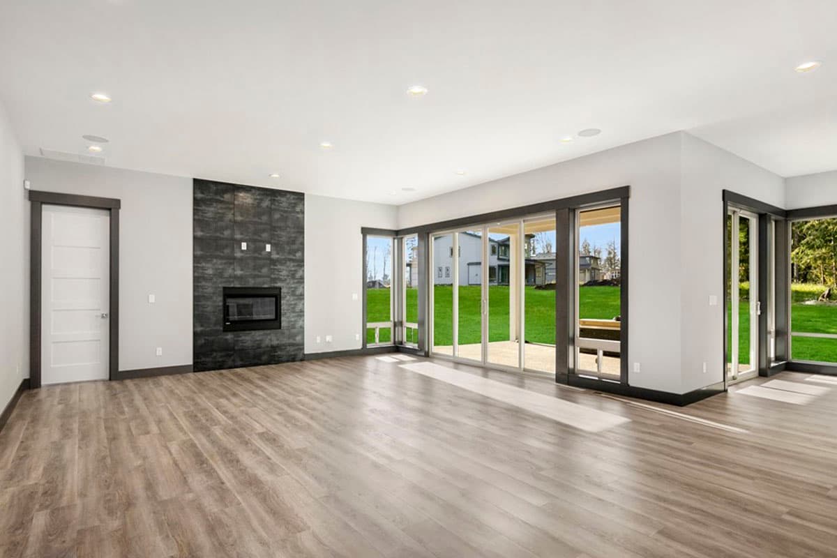 Open concept great room with fireplace, large windows, and sliding glass doors to the backyard.