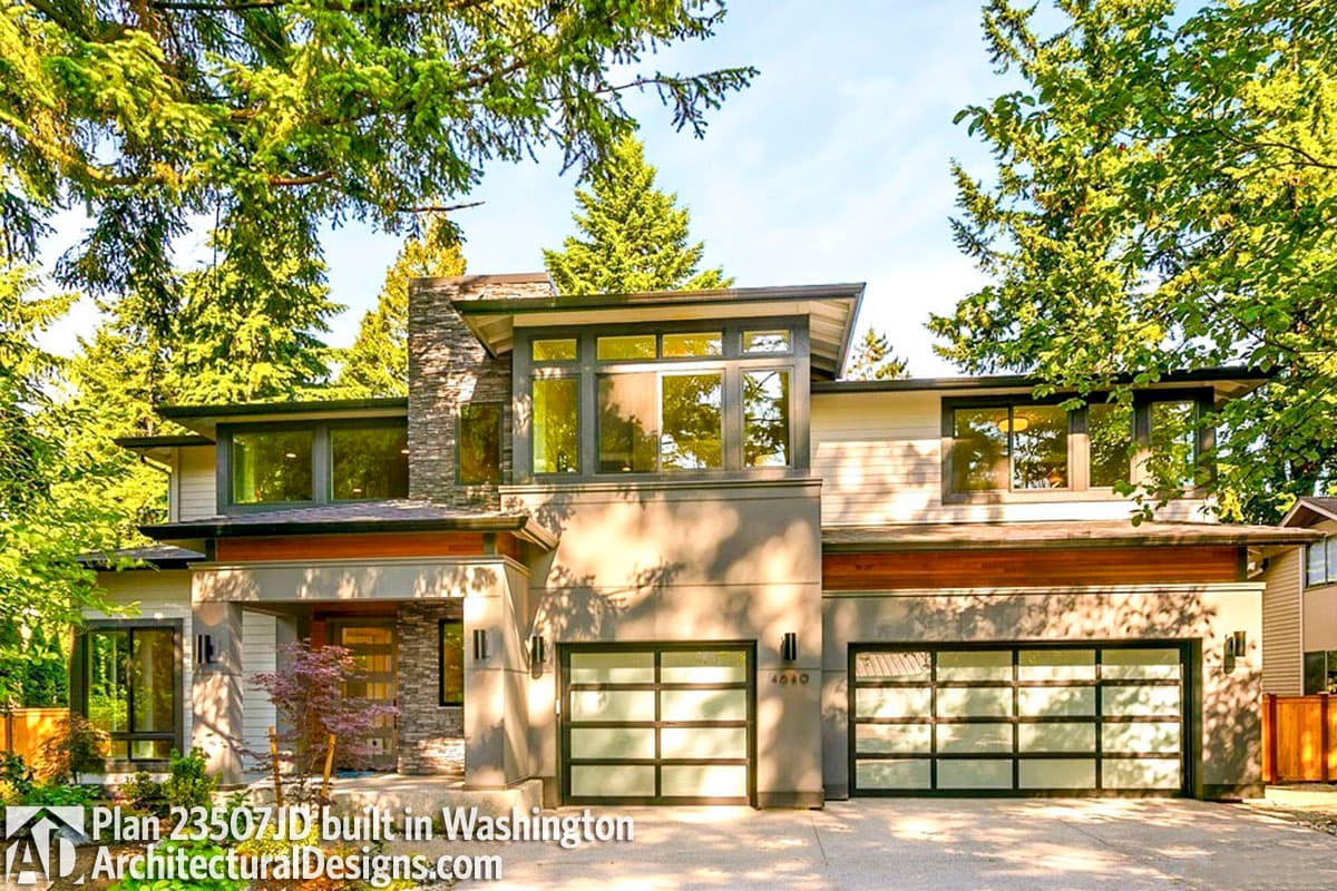 Modern house plan exterior with stone accents, cantilevered upper level, large windows, and two glass-paneled garage doors.