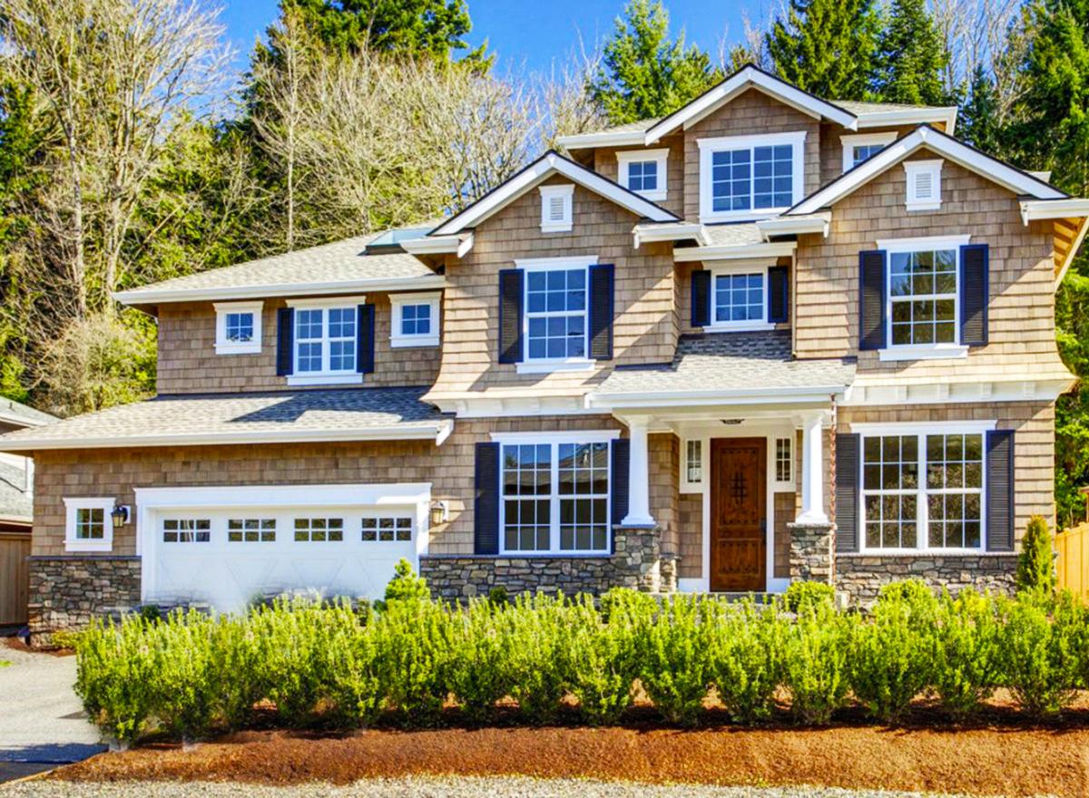 Craftsman style house plan exterior. Two stories, cedar shakes, stone accents, covered entry porch, and a multi-pane garage door.