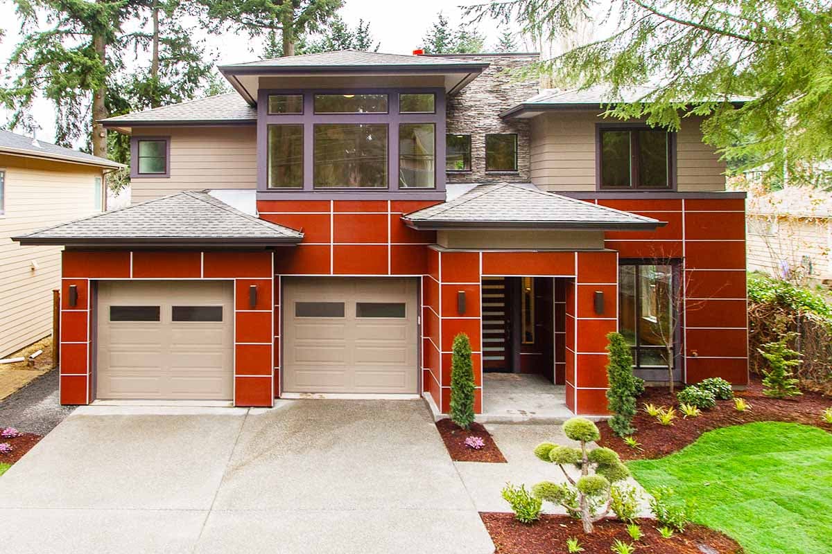 Modern two-story house plan exterior with dual garages, prominent red facade panels, stone accents, and large upper-level windows.