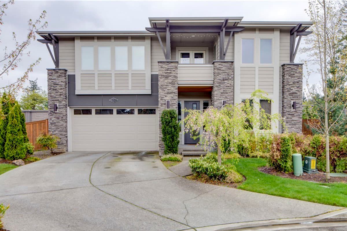 Two-story modern house plan exterior with stacked stone accents, a two-car garage, and cantilevered upper floor.