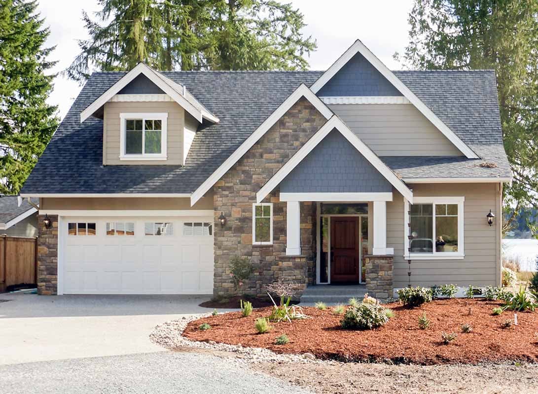 House plan exterior. Two-story home with Craftsman style elements. Features include gabled roof, stone facade, dormer, and attached garage.
