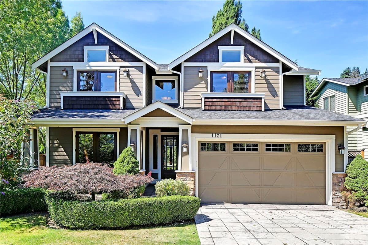 House plan exterior: Two-story home with gables, dormers, covered porch, stone accents, and a double garage.