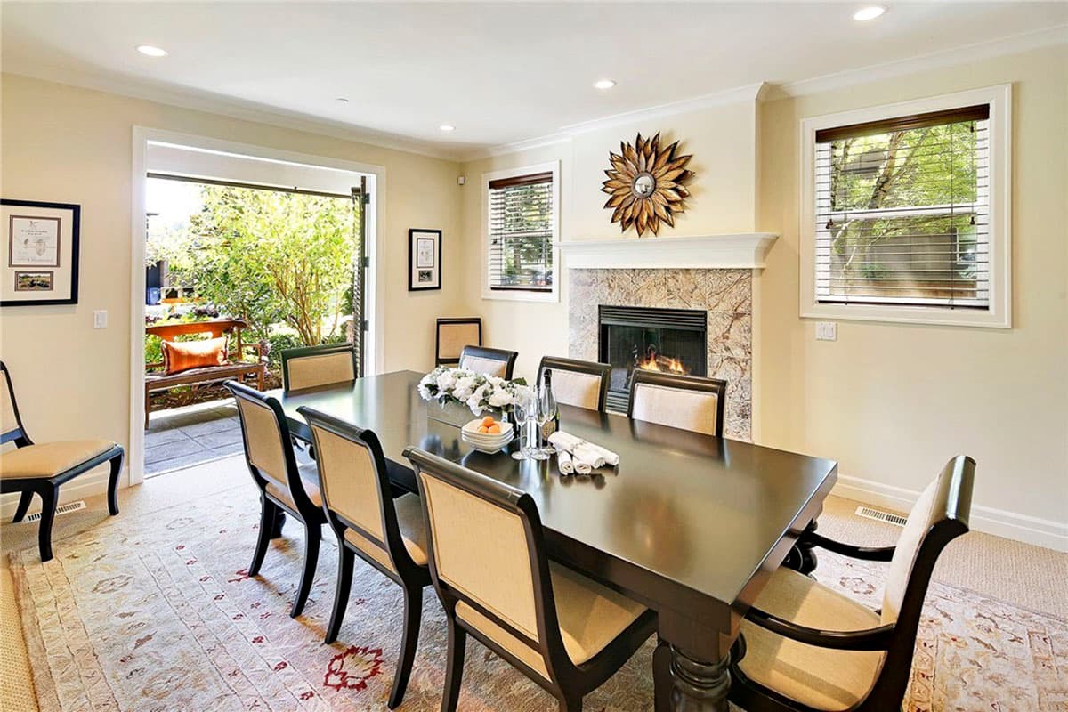 Dining room with fireplace, large table and chairs, French doors opening to patio and garden.