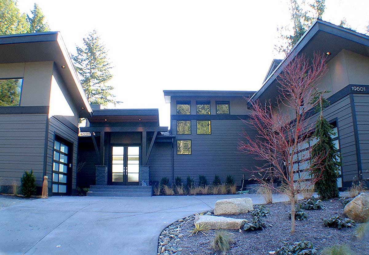 Modern house plan exterior with a two-car garage, expansive windows, and a covered entrance with double doors.