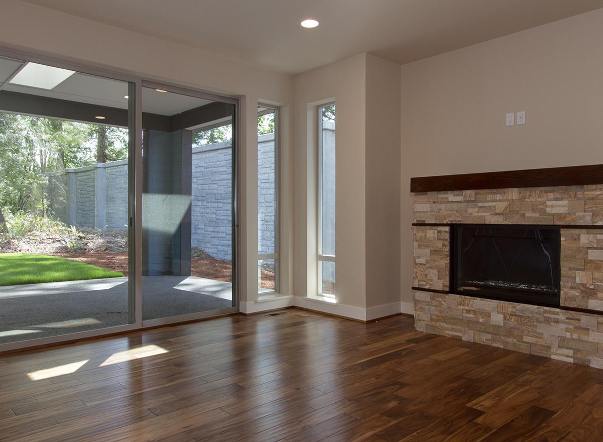 Interior view of living area with a stone fireplace, large sliding glass doors, and tall narrow windows.