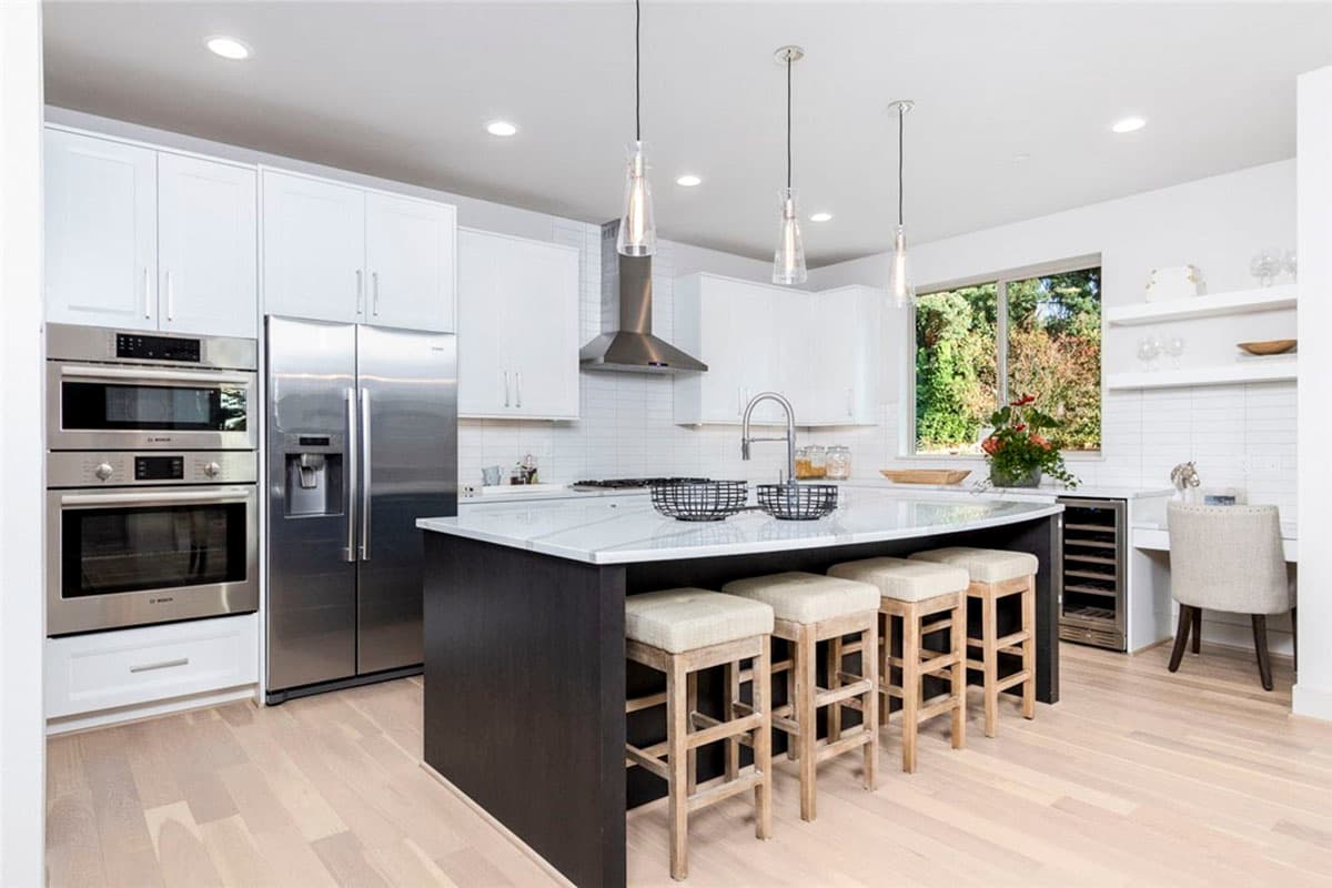 Modern kitchen with white cabinets, stainless steel appliances, large island with seating, and subway tile backsplash.