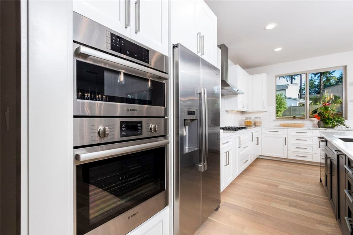 Kitchen interior with stainless steel Bosch appliances, white cabinetry, and hardwood floors.