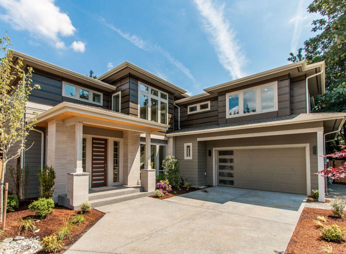 Modern house plan exterior with a covered entryway, multiple gables, and a two-car garage with glass panel doors.