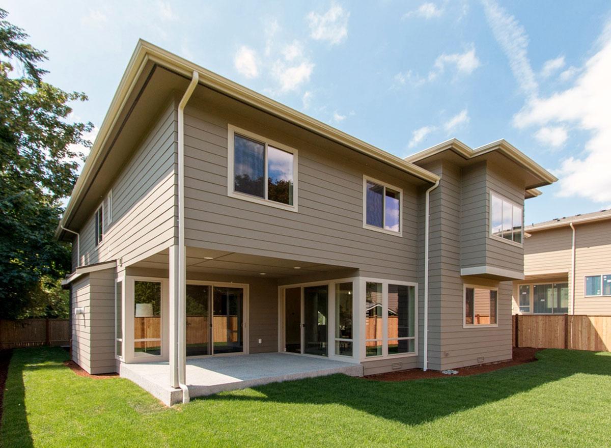 Two-story house plan exterior with covered patio, horizontal siding, and prominent rooflines.