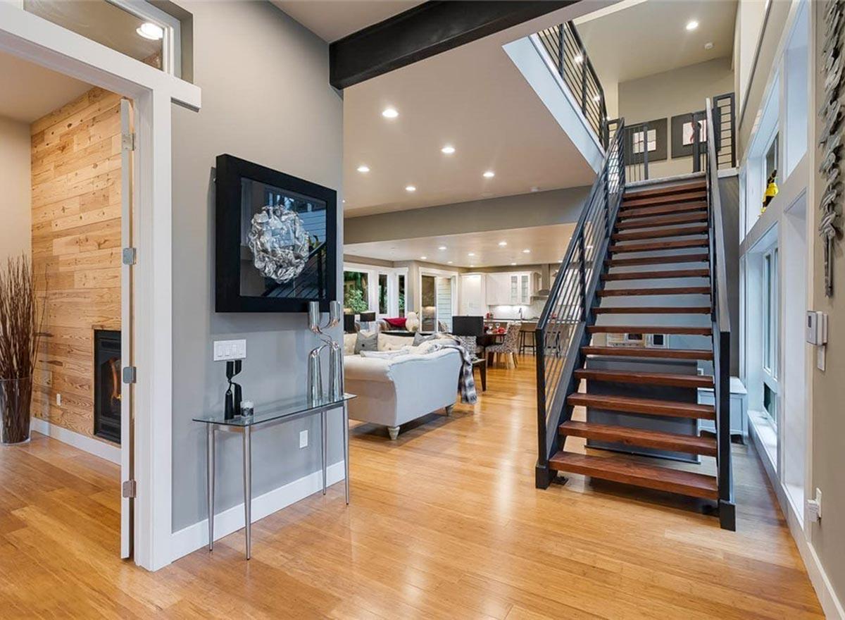Interior view of open concept living space with fireplace, stairs, and kitchen visible.