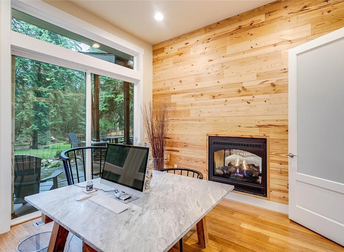 Home office with a gas fireplace set into a wood-paneled wall and large sliding glass doors.