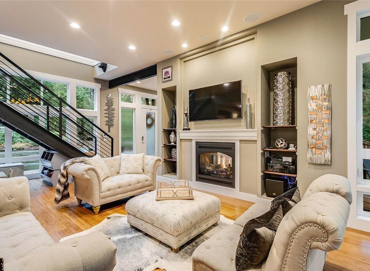 Contemporary living room with fireplace, television, modern staircase with metal railing, and plush seating.