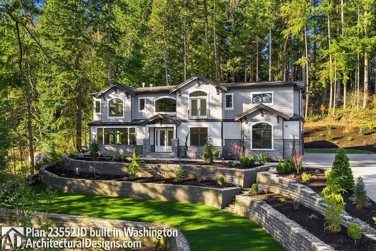 House plan exterior: Two-story Modern home with shingle siding, stone accents, arched windows, and a central covered entryway.
