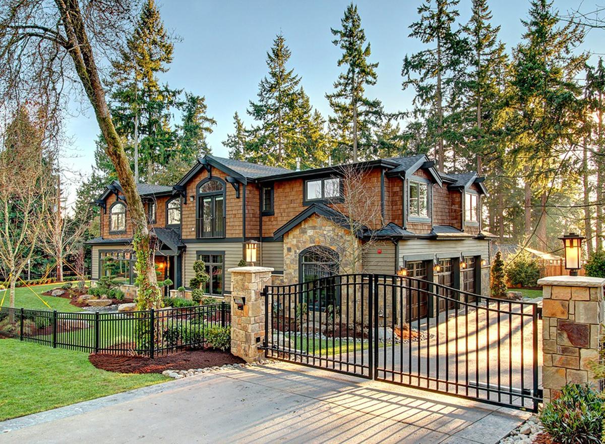House plan exterior: Two-story home with stone accents, cedar shingles, arched windows, gables, and a three-car garage.