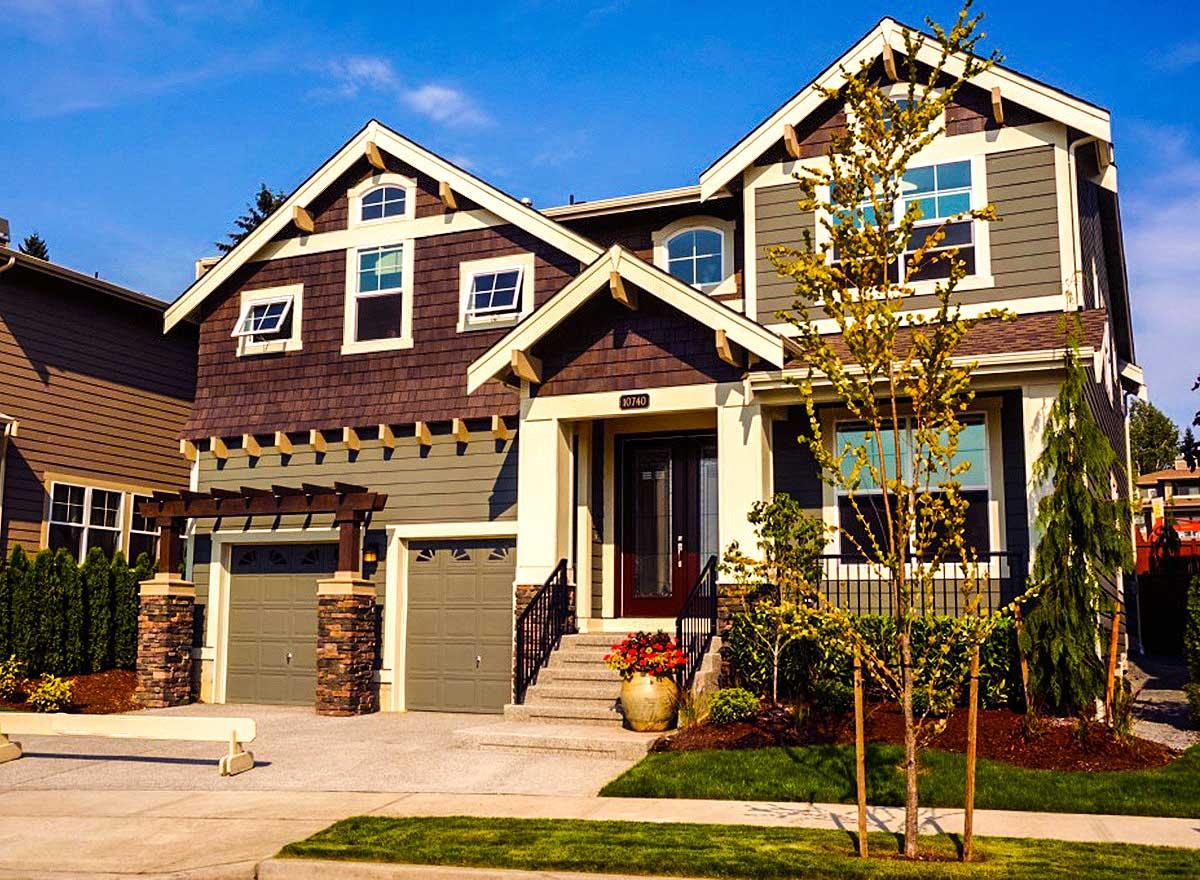 Two-story house plan exterior with dual garage doors, a covered entryway, and prominent gables with cedar shakes.