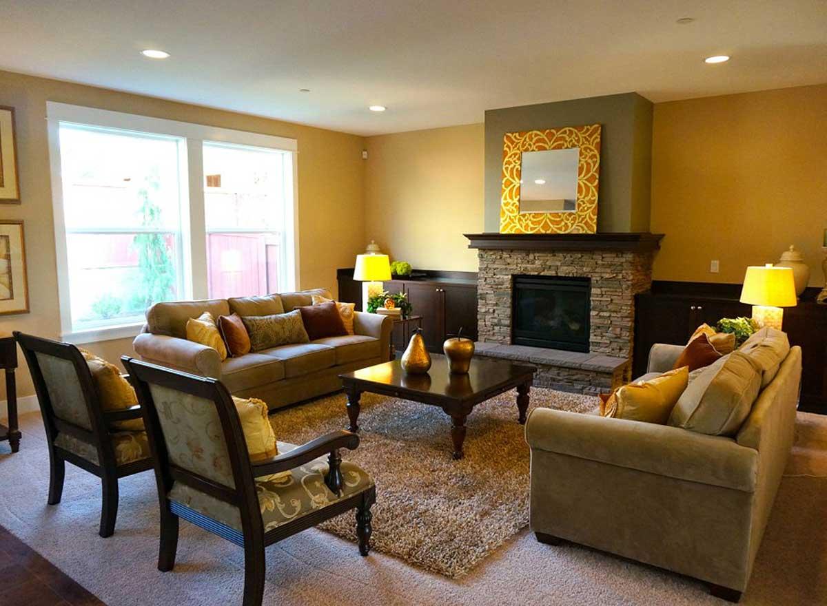 Living room with stone fireplace, comfortable seating, a large coffee table, and windows.