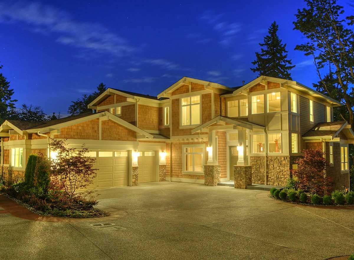 House plan exterior: Craftsman style, two stories, cedar shake siding, stone accents, covered entry, and a three-car garage.